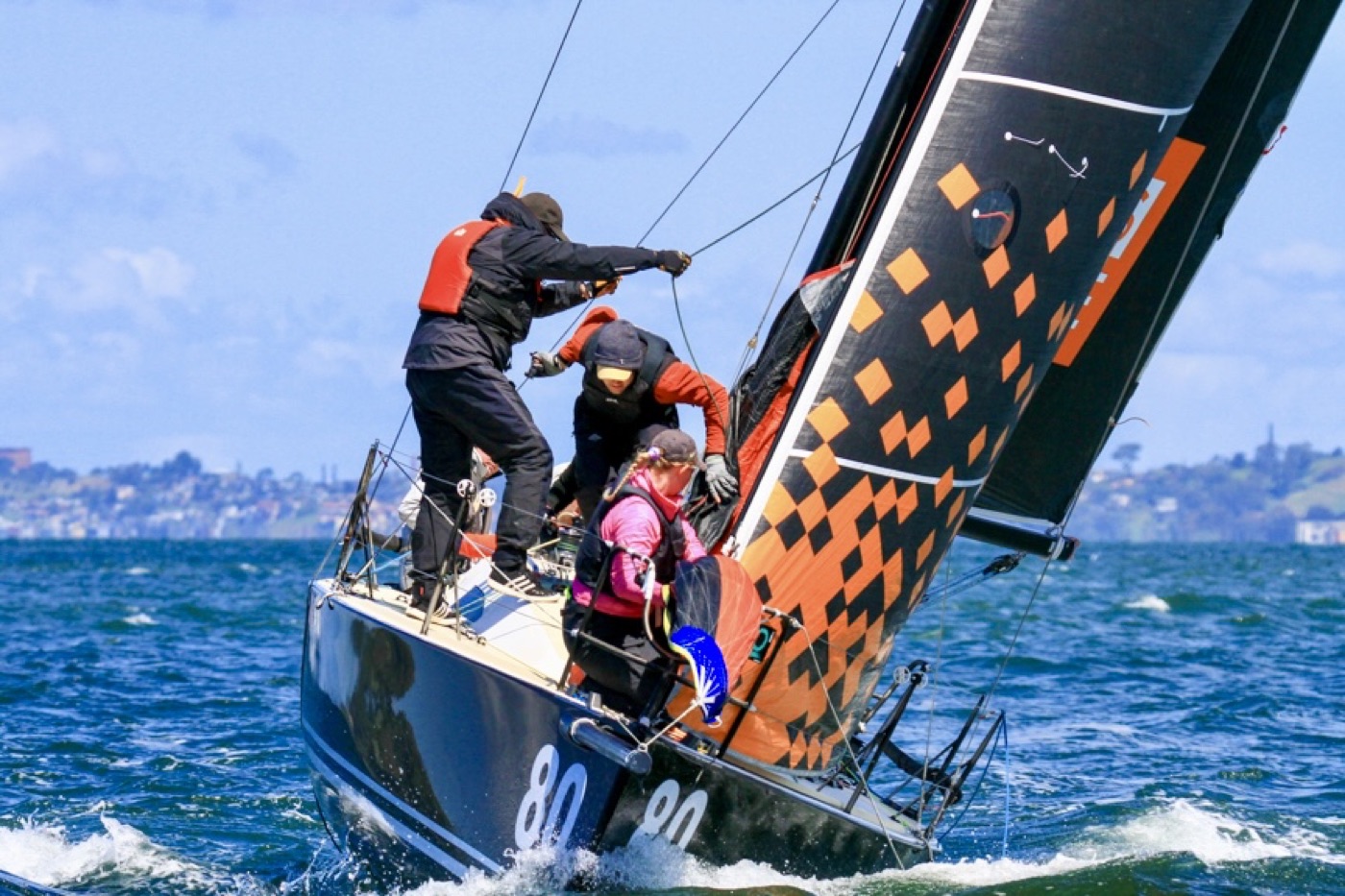 A sailing crew working a heeled-over keelboat in big breeze